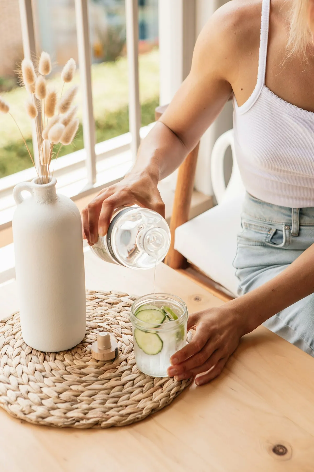 Woman pouring water into a glass at home in Los Angeles, mobile IV therapy and hydration recovery