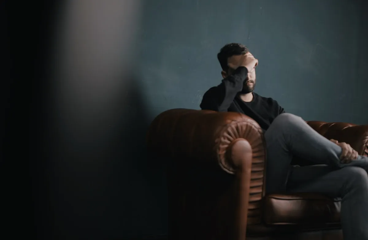 Person experiencing hangxiety sitting with head in hands the morning after drinking in Los Angeles