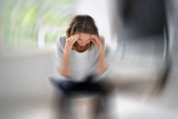 Woman experiencing dizziness and headaches from dehydration, a common symptom of dehydration.