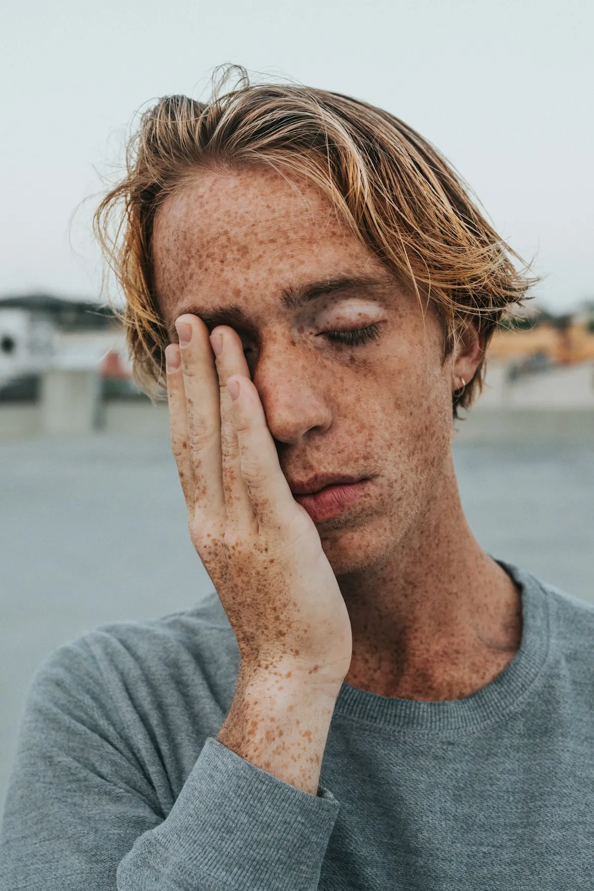 Man feeling fatigued and covering his face, a common sign of a weakened immune system in Los Angeles
